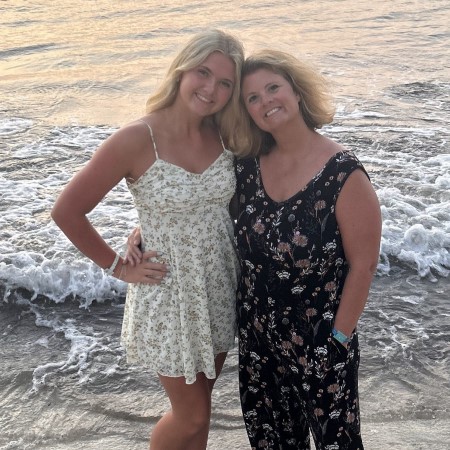Mother and daughter standing together and smiling on a beach